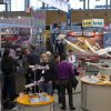 Fachbesucher begutachten die neuen Modellflugzeuge von Hitec. / Trade fair visitors examine the new model planes by Hitec.