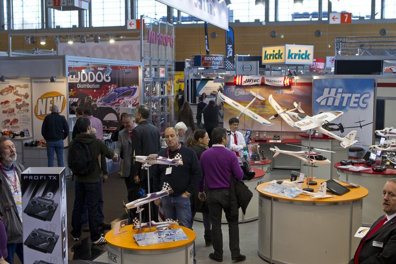 Fachbesucher begutachten die neuen Modellflugzeuge von Hitec. / Trade fair visitors examine the new model planes by Hitec.