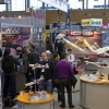 Fachbesucher begutachten die neuen Modellflugzeuge von Hitec. / Trade fair visitors examine the new model planes by Hitec.